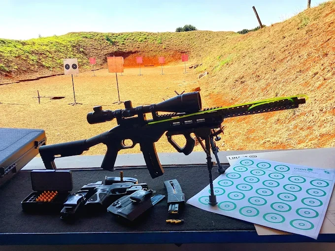 Fotografia real do estande da ATIRAR com rifle de precisão e alvos na pista
